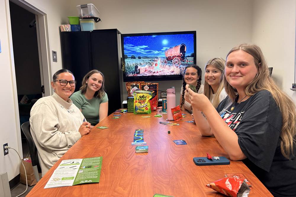 Lab members playing a card game around the conference table with snacks
